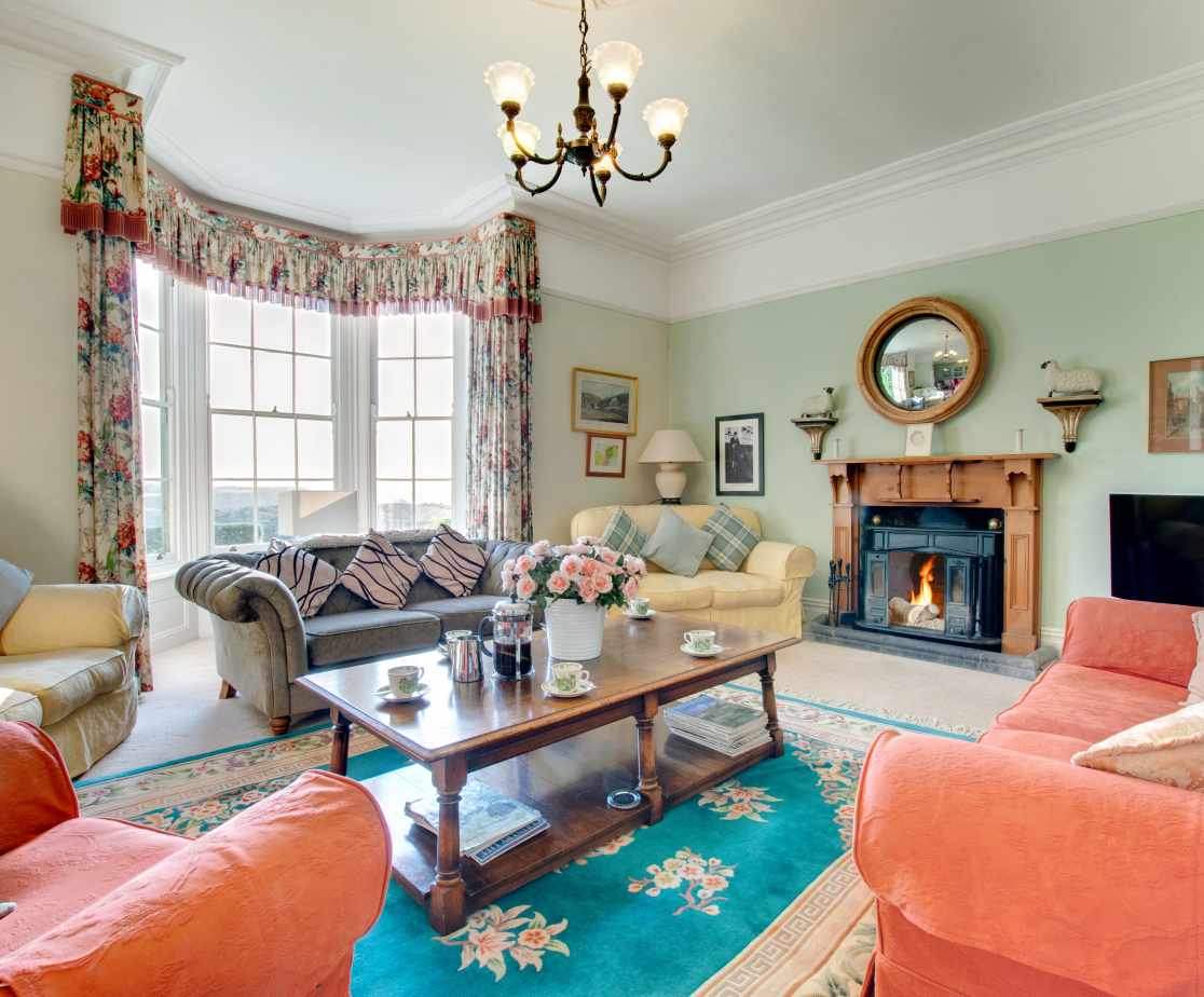 The large drawing room with bay window looking out over the lawns and sea views beyond.